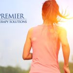 Back view of a woman running outdoors in sunlight, Premier Therapy Solutions logo on left.