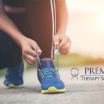 Person tying running shoe laces, promoting physical therapy services with Premier Therapy Solutions logo displayed.