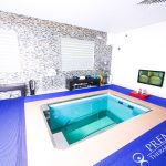 Hydrotherapy pool in a bright therapy room with modern equipment and colorful mats.