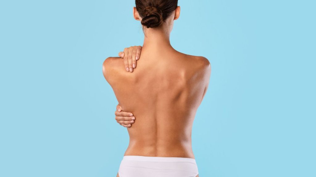 a woman with scoliosis holding her back