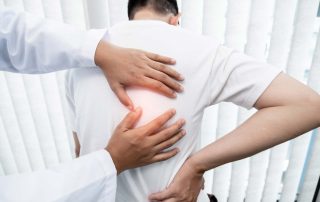 Physical therapist examining patient's back pain with hands, focusing on spine treatment and relief.