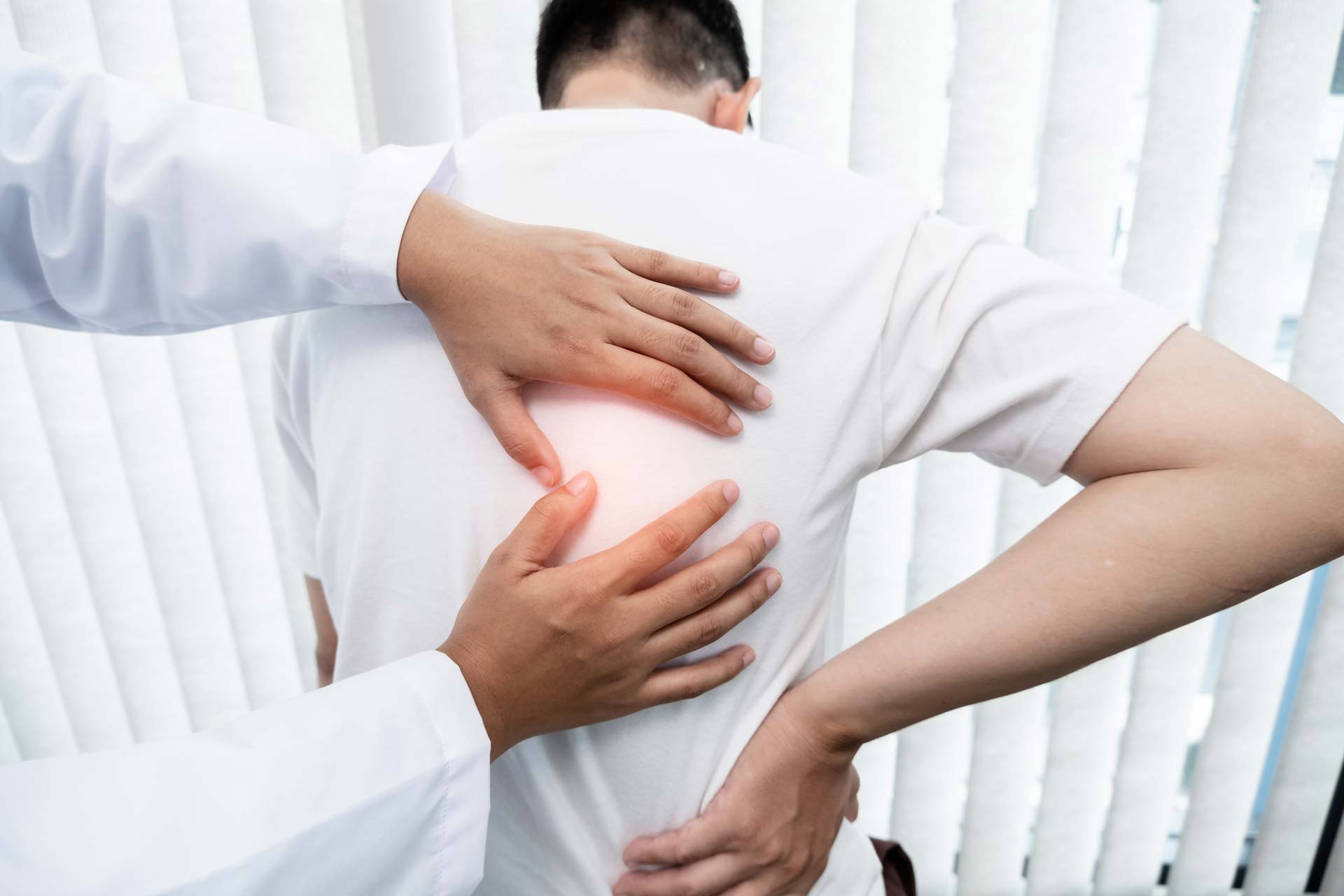 Physical therapist examining patient's back pain with hands, focusing on spine treatment and relief.