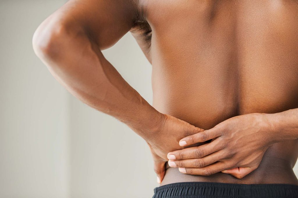 Person holding lower back in pain, indicating discomfort or backache.