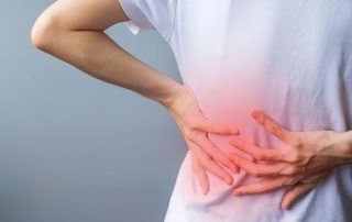 Person holding lower back in pain, indicating eds and scoliosis, with a red highlighted area on the back.