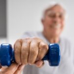 Strength Training During Post Surgical Rehabilitation - Premier Therapy Boca Raton Senior man holding a blue dumbbell during post surgical rehabilitation session