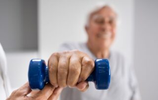 Senior man holding a blue dumbbell during post surgical rehabilitation session