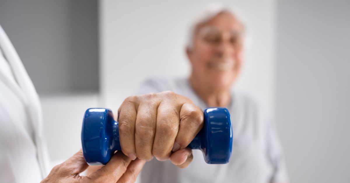 Strength Training During Post Surgical Rehabilitation - Premier Therapy Boca Raton Senior man holding a blue dumbbell during post surgical rehabilitation session