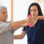 Holistic Physical Therapy for Seniors – Strength & Mobility - Premier Therapy Boca Raton Senior woman performing arm strengthening exercises with assistance from therapist