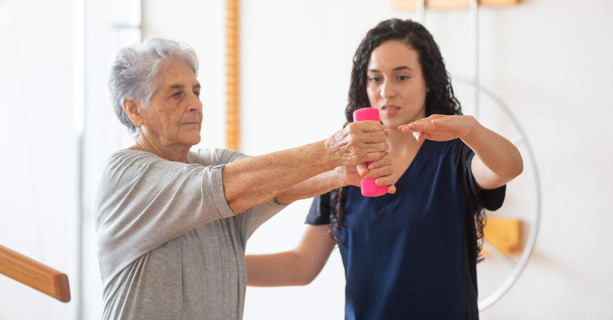 Senior woman performing arm strengthening exercises with assistance from therapist
