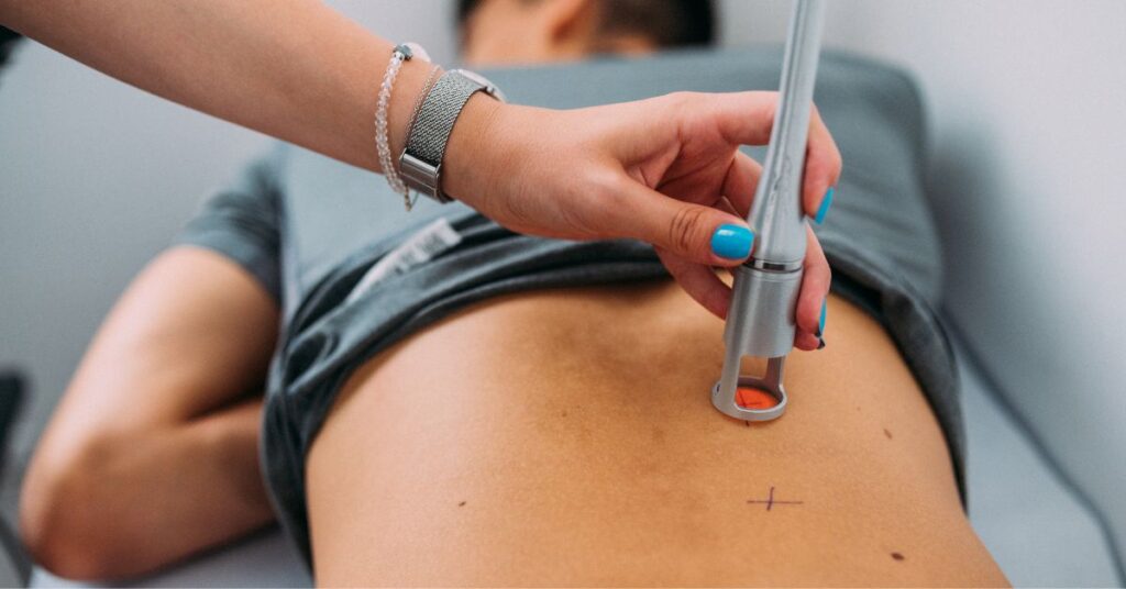 Deep tissue laser therapy device targeting lower back pain during a professional treatment session.