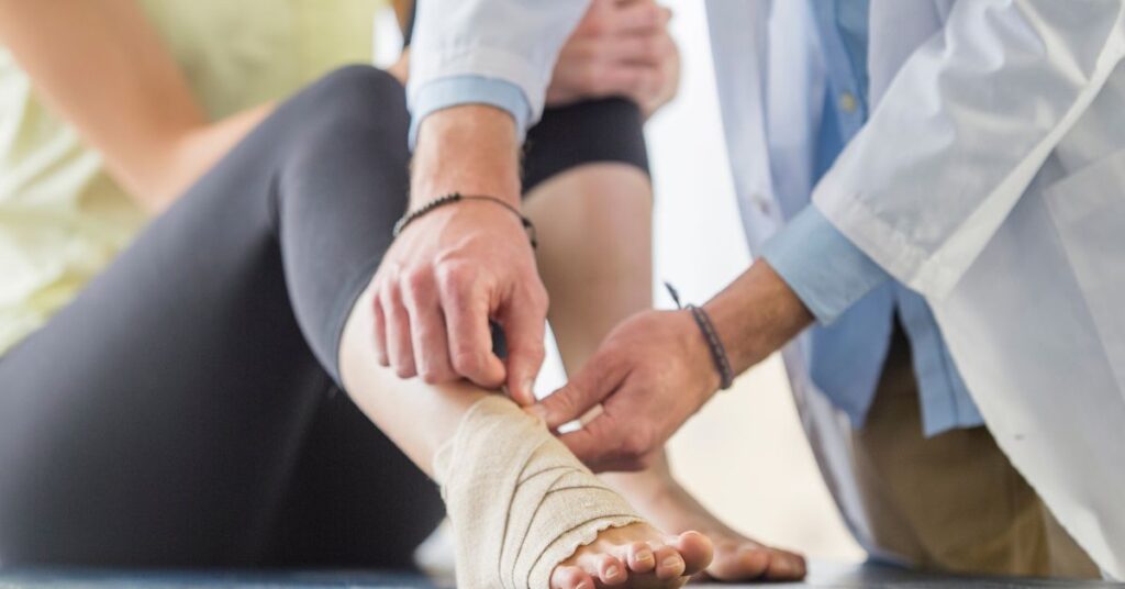 Ankle Injury Support by Injury Specialist - Premier Therapy Boca Raton Injury specialist applying compression bandage to support ankle injury recovery